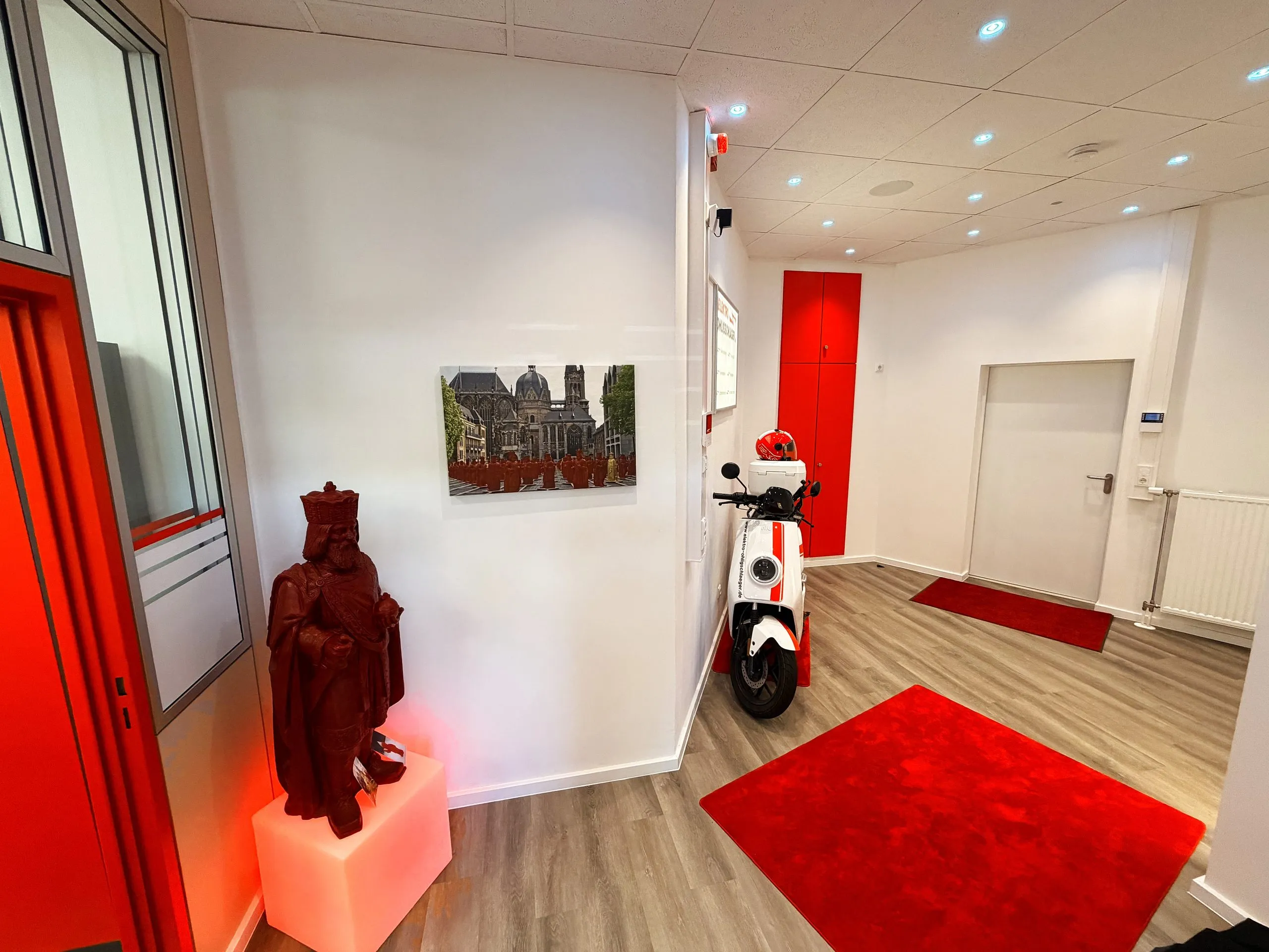 Showroom und Eingangsbereich der Zweigniederlassung Alsdorf mit E-Roller, rotem Teppich und der Karls-Statue